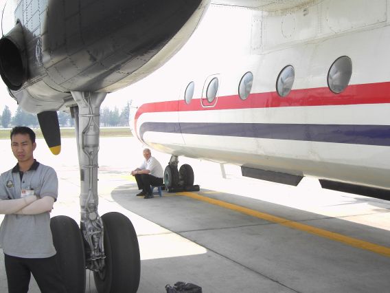 President Airlines Antonov 24 auf einer Außenposition in Bangkok, einer der Piloten sitzt unter dem Flugzeug