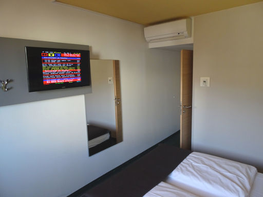 B&B Hotel Hannover-Nord, Hannover, Deutschland, Zimmer 211 mit Flachbildfernseher, Wandspiegel, Klimaanlage, Eingangstür und Trennwand zum Bad