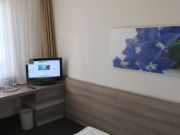 H+ Hotel Frankfurt Airport West, Deutschland, Zimmer 254 mit Doppelbett, Fenster, Tisch, Stuhl und Fernseher