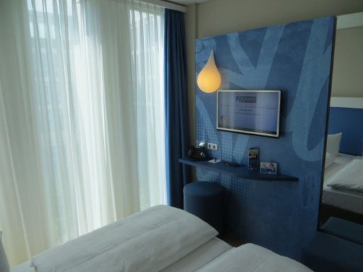 H2 Hotel München Messe, Deutschland, Zimmer 217 mit kleinem Tisch, Hocker, Flachbildfernseher und Wandspiegel