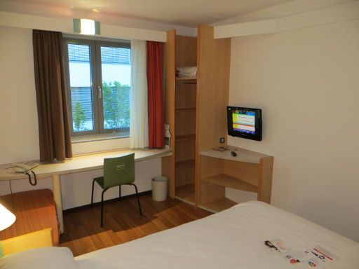 ibis Stuttgart City, Stuttgart, Deutschland, Zimmer 311 mit Doppelbett, Nachttischleuchten, Kofferablage, Fenster, Tisch, Stuhl und offenen Wandschrank