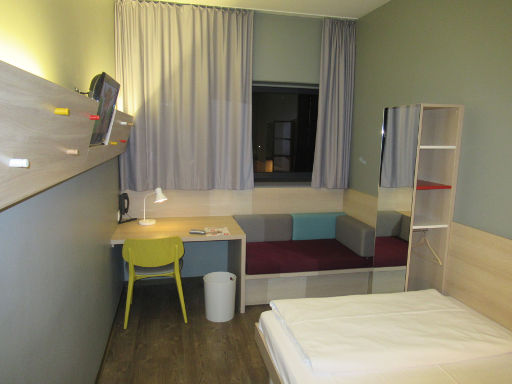 MEININGER Hotel Berlin Airport, Berlin, Deutschland, Zimmer 119 mit Flachbildfernseher, Fenster, Schreibtisch, Stuhl, Sitzbank, Schrank und Wandspiegel