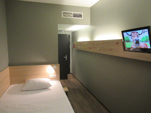 MEININGER Hotel Berlin Airport, Berlin, Deutschland, Zimmer 119 mit Einzelbett, Nachttischleuchte, Trennwand zum Bad, Klimaanlage und Eingangstür