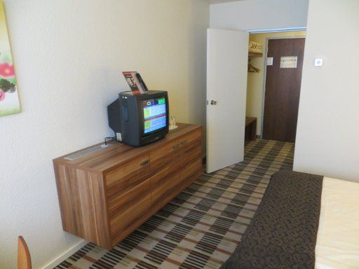 Mercure Hotel Saarbrücken Süd, Deutschland, Zimmer 230 mit Fernseher, offener Wandschrank, Eingangstür und Trennwand zum Bad