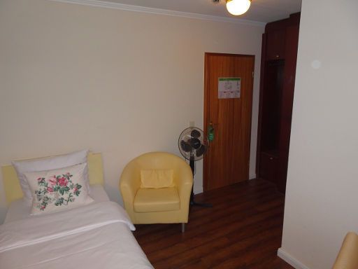 Parkhotel Rosarium, Uetersen, Deutschland, Zimmer 106 mit Einzelbett, Sessel, Ventilator, Eingangstür und Trennwand zum Bad