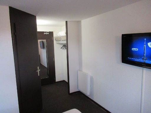 Enzo Hotels Vierzon by Kyriad Direct, Vierzon, Frankreich, Zimmer 33 mit Tür zum Bad, Eingangstür, Wandspiegel, Garderobe, Heizkörper und Flachbildfernseher