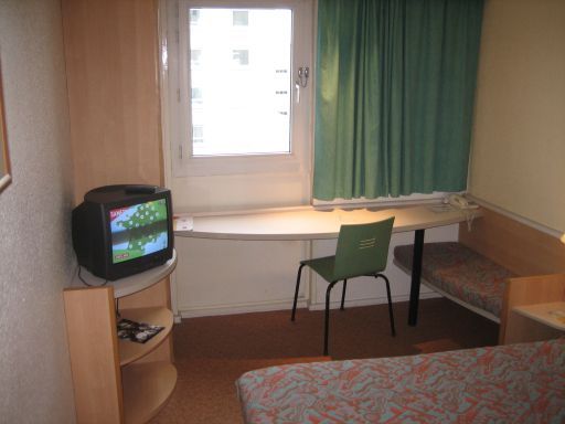 ibis Porte d’Orléans, Paris, Frankreich, Doppelbett, Fernseher, Tisch, Stuhl, Fenster und Sitzbank