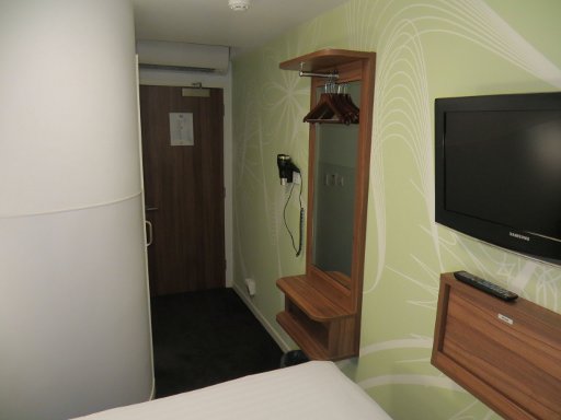Tune Hotel Liverpool Street, London, Großbritannien, Zimmer 19 mit Eingangstür, Trennwand zum Bad, Föhn, Garderobe und Spiegel