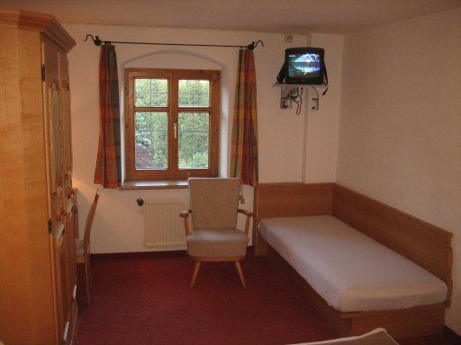 Gasthof zum Schupfen, Innsbruck, Österreich, Zimmer 4 mit Kinderbett, Stuhl, Tisch, Schrank, Fenster, Fernseher