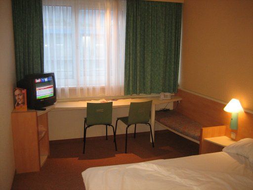 Ibis Linz, Österreich, Doppelbett, Zimmer 409 mit Bett, Fernseher, Tisch, zwei Stühlen, Fenster, Kofferablage und Sitzgelegenheit