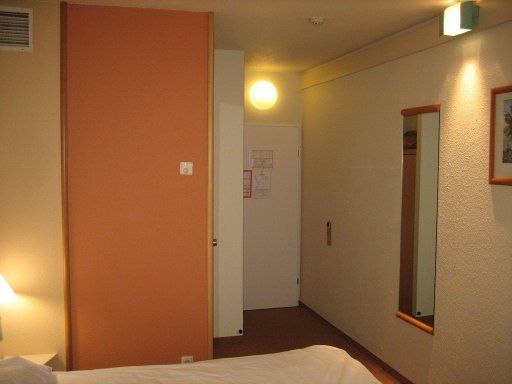 Ibis Linz, Österreich, Zimmer 409 mit Badezimmertür, Eingangstür, Wandspiegel und Schrank neben der Tür
