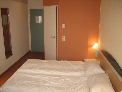 Ibis Salzburg Nord, Salzburg, Österreich, zwei Einzelbetten, Eingang und Wand zum Bad, großer Spiegel und Zimmereingang