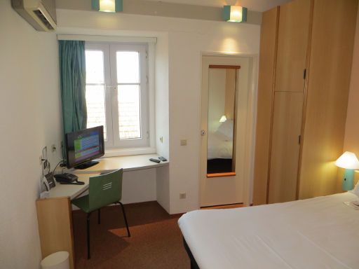 ibis Figueira da Foz Centro, Portugal, Zimmer 308 mit Fenster, Stuhl und Tisch, Flachbildfernseher und Tür zum Badezimmer