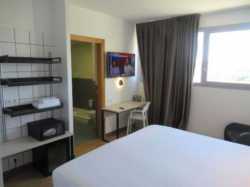 B&B Hotel Miranda de Ebro, Miranda de Ebro, Spanien, Zimmer 204 mit Regal, Minisafe, lautloser K&uuml;hlschrank, T&uuml;r zum Bad, Fernseher, Tisch und Stuhl