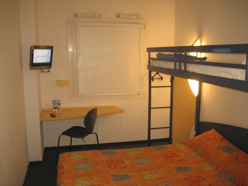 ibis budget Madrid Valentin Beato, Spanien, Zimmer 215 mit Queen Size Bett, Fenster, Stuhl, Tisch und Flachbild Fernseher