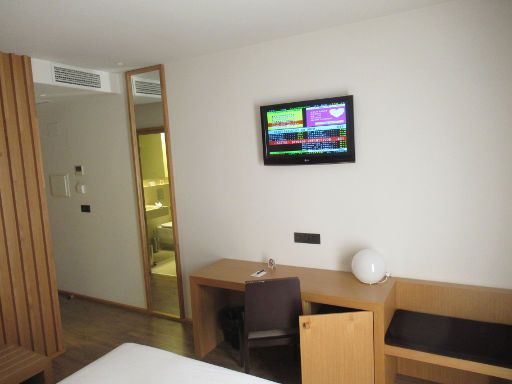 Hotel Araba, Vitoria-Gasteiz, Spanien, Zimmer 01 mit Klimaanlage, Wandspiegel, Schreibtisch, Stuhl, Kofferablage, Flachbildfernseher, Kühlschrank und Sitzbank