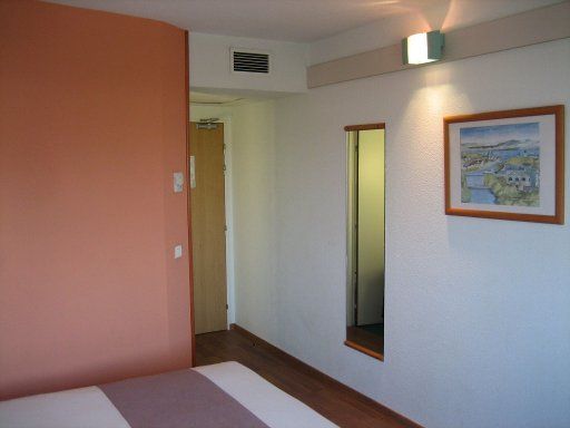 ibis Barcelona Cornellà, Spanien, Zimmer 301 mit Wandspiegel, Eingangstür, Klimaanlage und Wand zum Bad