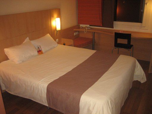 Ibis Madrid Valentin Beato, Spanien, Zimmer 204 mit Doppelbett, Fenster, Stuhl, Tisch und Kofferablage