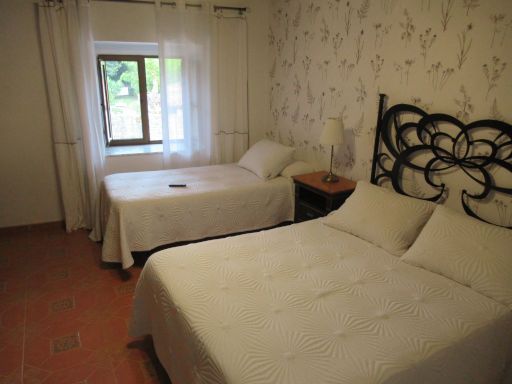 Pension Restaurant Casa Paulino, Los Corrales de Buelna, Spanien, Zimmer 101 mit gro&szlig;em Bett und Einzelbett, Nachttisch mit Leuchte, Fenster und Gardine
