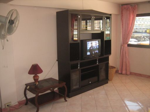 Dolphin Apartment, Zimmer Nummer 12, Pattaya, Thailand, Wohnzimmer mit Ventilator, kleiner Tisch und Wandschrank mit einem Fernseher