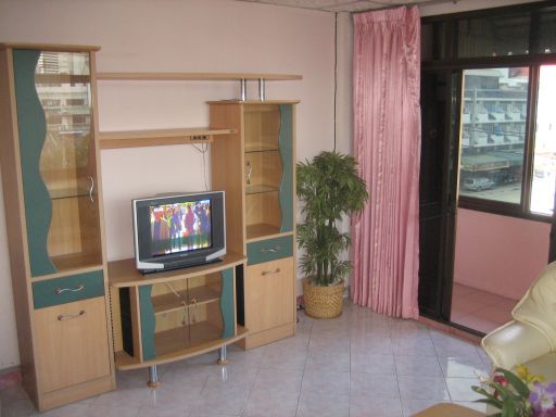 Dolphin Apartment, Pattaya, Thailand, Wohnzimmer mit Fernseher, Wandschrank, künstlicher Blume und Schiebetür zum Balkon