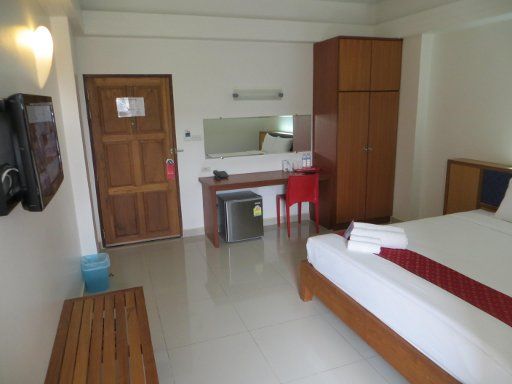 J2 Hotel, Mae Sot, Thailand, Zimmer 102 mit Flachbildfernseher, Ablage, Eingangstür, Kühlschrank, Schreibtisch, Stuhl, Wandspiegel und Schrank